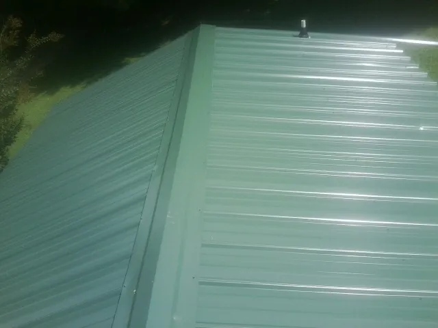 New green metal panels meeting at the ridge of a roof — Flat Roof Repair work by our crew in Boswell