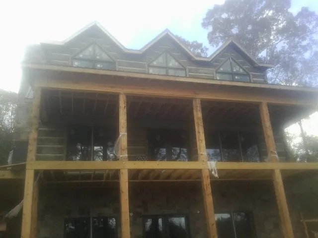 Dormers and porch framing on a large log home under construction — Roof Coating work by our crew in Boswell