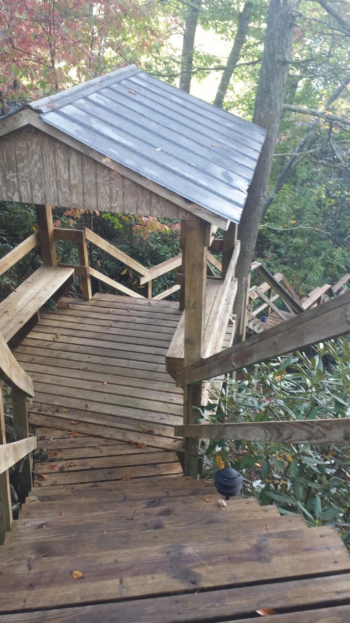 Metal roofed shelter over wooden steps on a wooded walkway — Skylight Repair & Installation work by our crew in Boswell