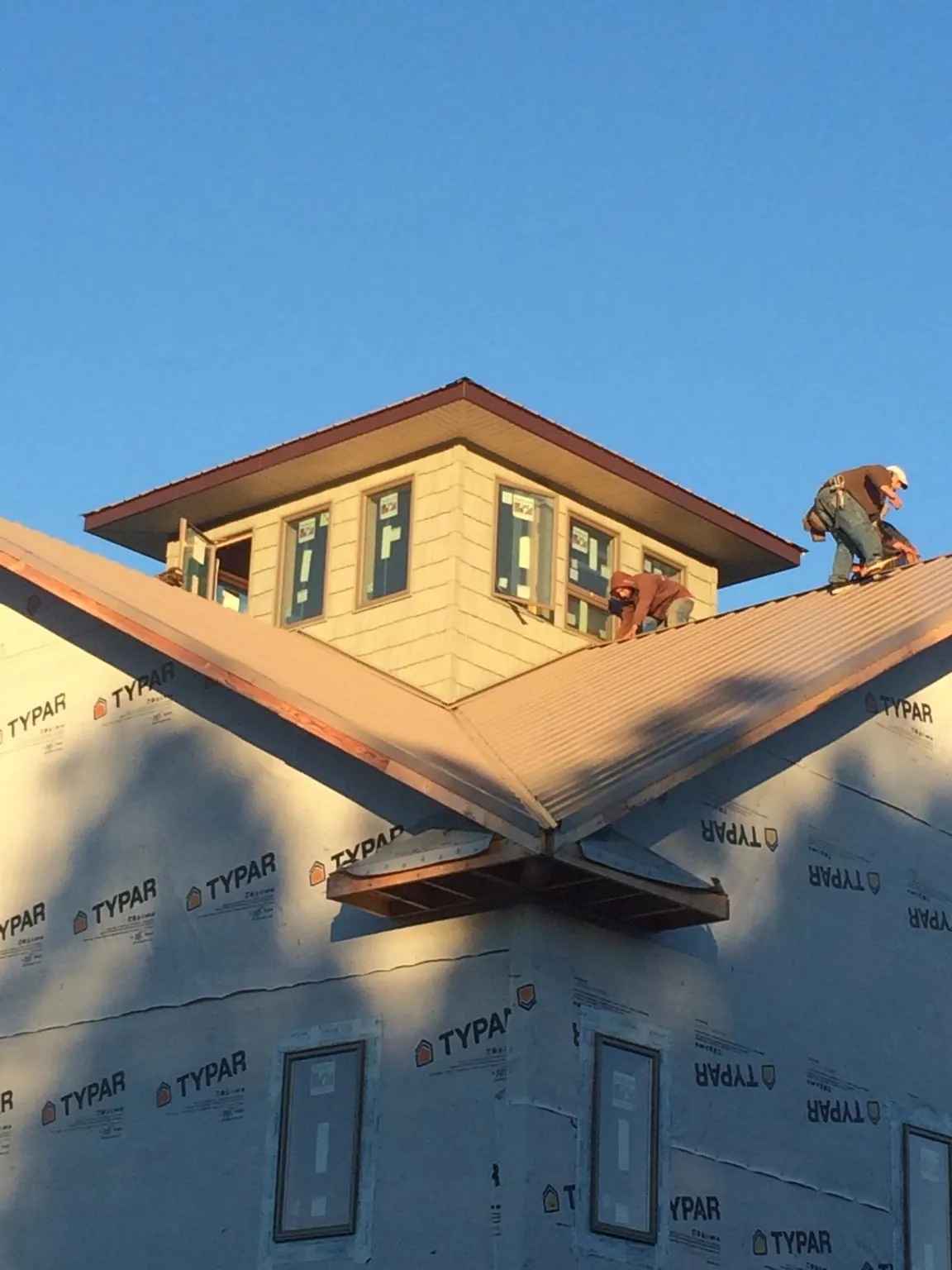 Roofers working around a rooftop cupola on a new metal roof at sunset — Roof Waterproofing in Boswell by Roofing Brothers
